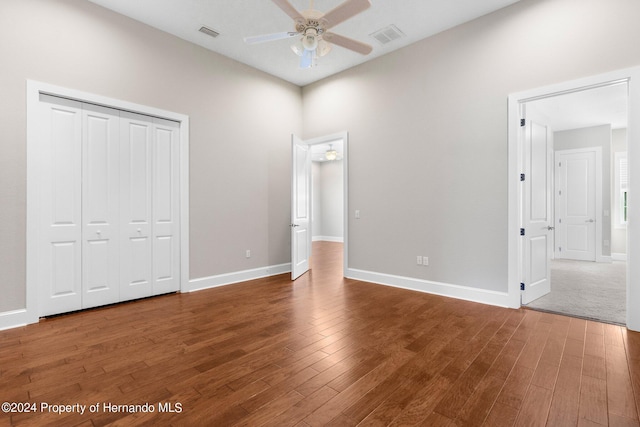 unfurnished bedroom with dark wood-type flooring, ceiling fan, and a closet