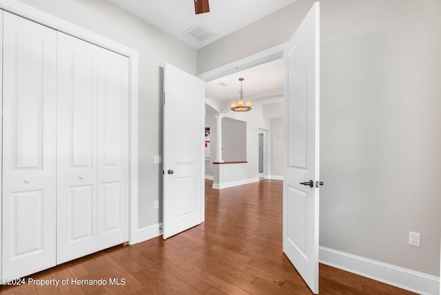 hallway with wood-type flooring and an inviting chandelier