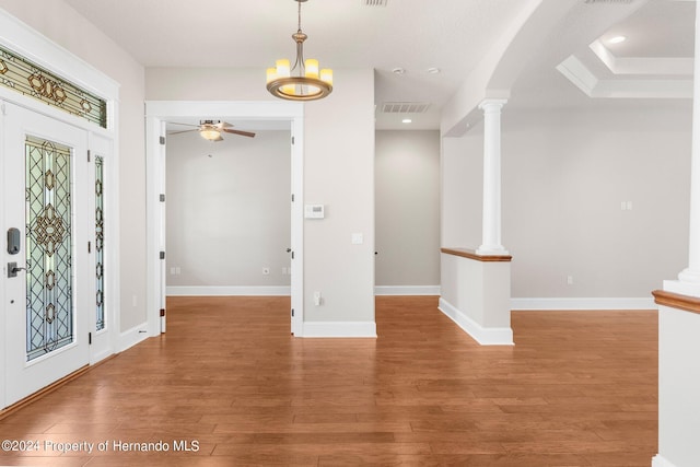 entryway featuring decorative columns, hardwood / wood-style flooring, and ceiling fan with notable chandelier