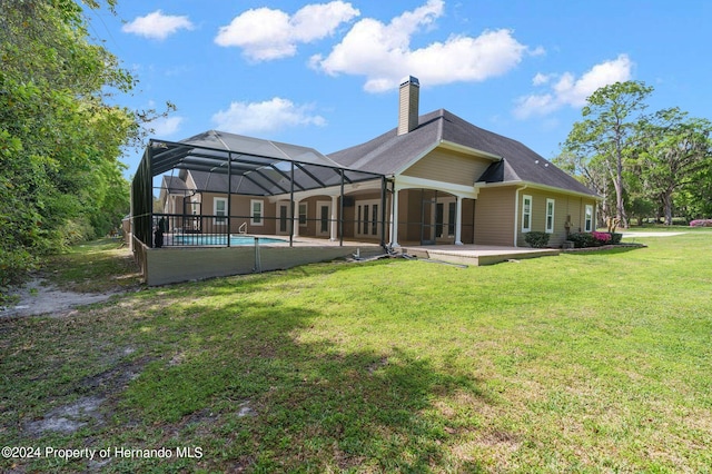 rear view of property featuring glass enclosure, a patio area, and a lawn