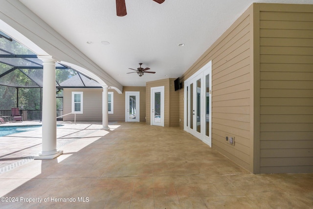 view of patio with glass enclosure, french doors, and ceiling fan