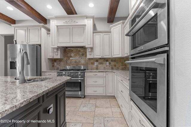 kitchen featuring light stone counters, decorative backsplash, beamed ceiling, white cabinetry, and appliances with stainless steel finishes