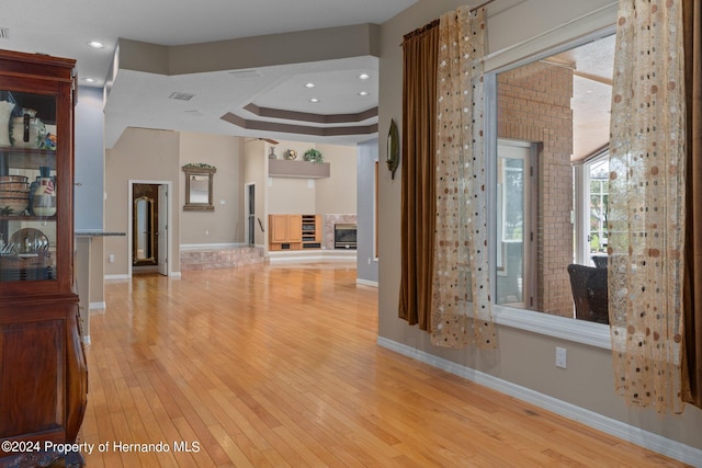 unfurnished living room featuring a raised ceiling and light hardwood / wood-style flooring