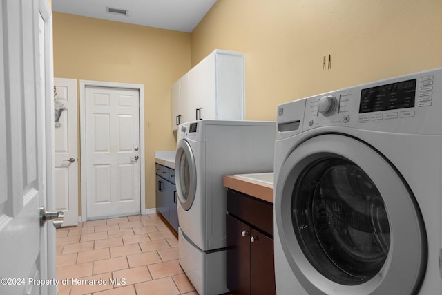 washroom featuring cabinets, light tile patterned floors, and washer and clothes dryer