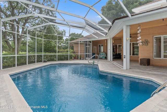 view of pool with ceiling fan, glass enclosure, and a patio area