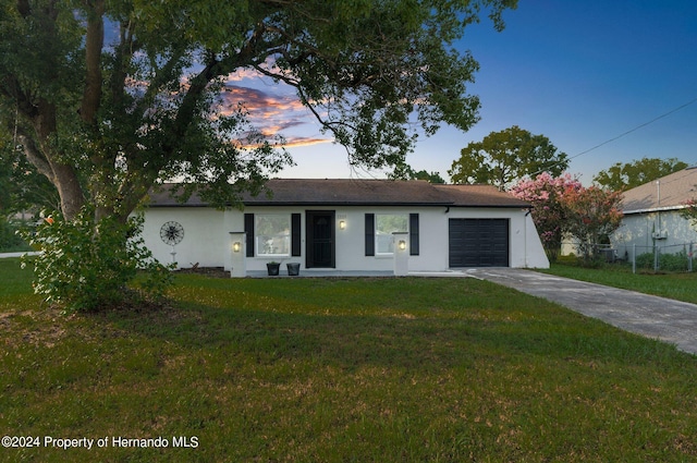 ranch-style house with a garage and a yard