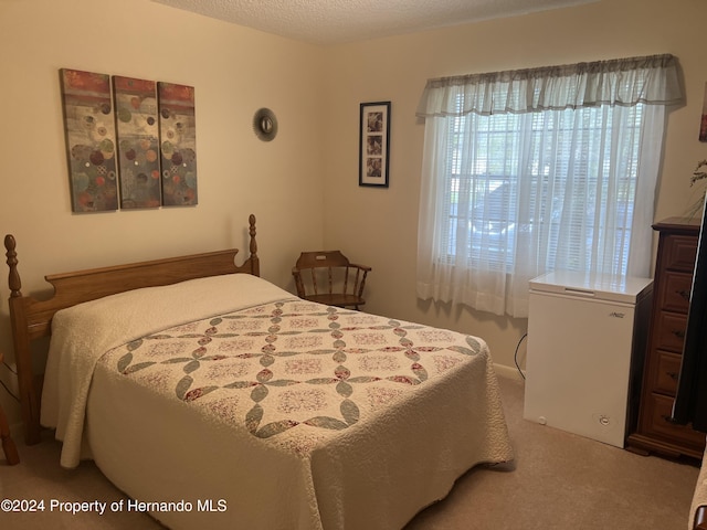 bedroom with fridge, a textured ceiling, and carpet floors