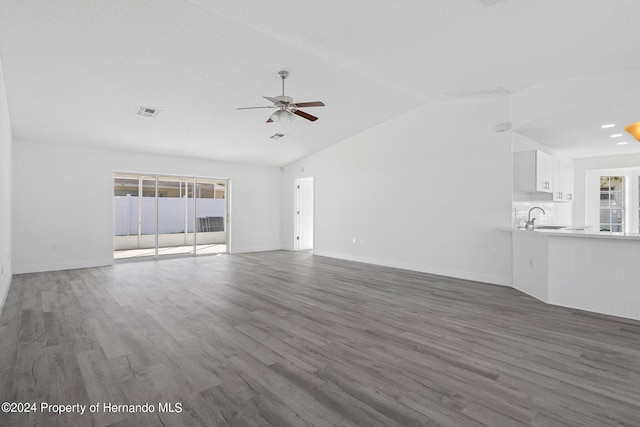 unfurnished living room featuring lofted ceiling, a textured ceiling, sink, dark hardwood / wood-style floors, and ceiling fan