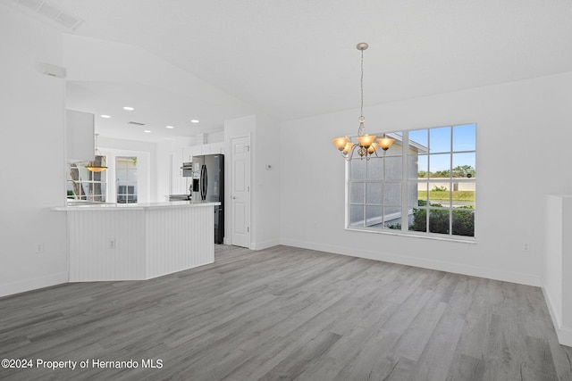 unfurnished living room featuring a chandelier and light wood-type flooring