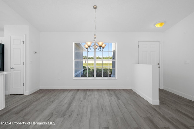 unfurnished dining area with a notable chandelier and dark hardwood / wood-style floors