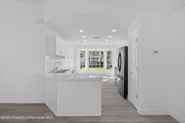 kitchen featuring stainless steel refrigerator, sink, white cabinets, kitchen peninsula, and light hardwood / wood-style flooring