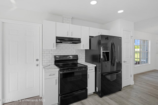 kitchen featuring light stone counters, white cabinets, decorative backsplash, black appliances, and light hardwood / wood-style flooring