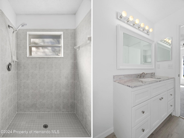 bathroom with vanity, a textured ceiling, a tile shower, and wood-type flooring