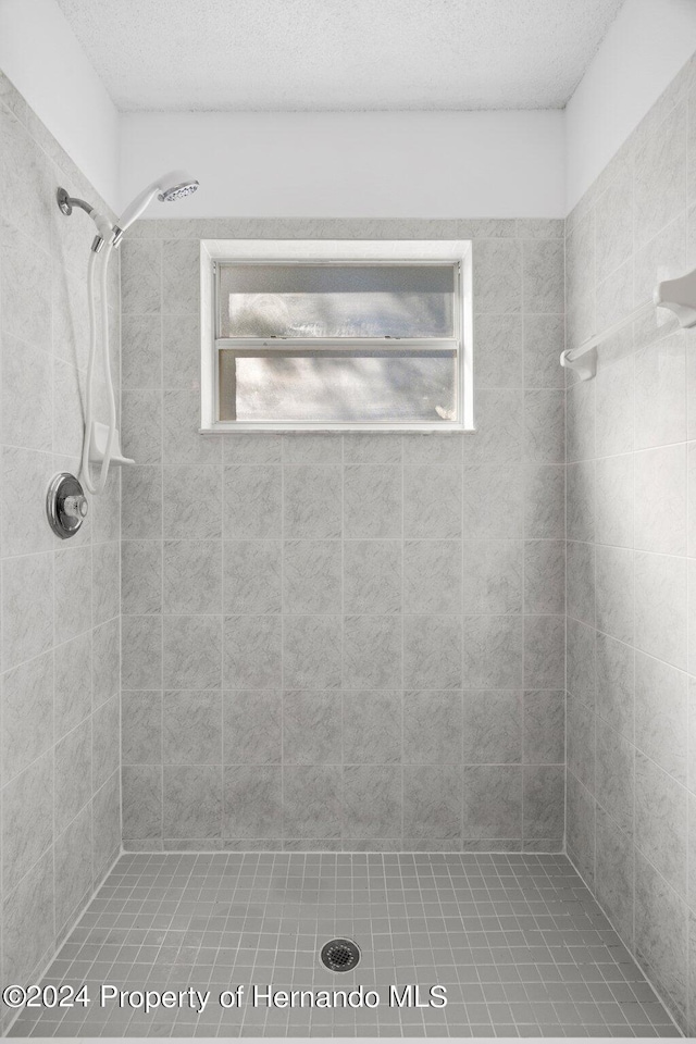 bathroom featuring tiled shower and a textured ceiling