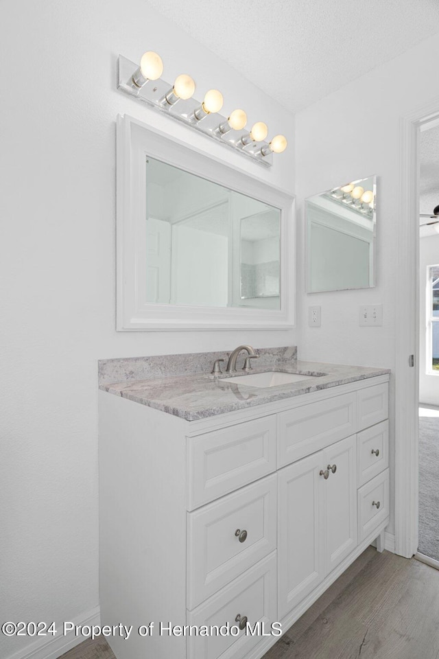 bathroom featuring vanity, hardwood / wood-style flooring, ceiling fan, and a textured ceiling