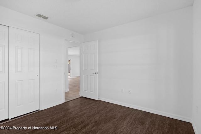 unfurnished bedroom with dark hardwood / wood-style flooring and a closet