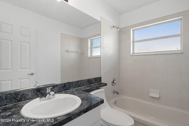 full bathroom featuring tiled shower / bath, toilet, and vanity