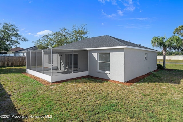 back of property with a sunroom and a lawn