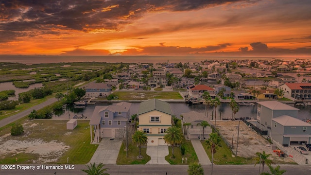 aerial view at dusk featuring a residential view and a water view