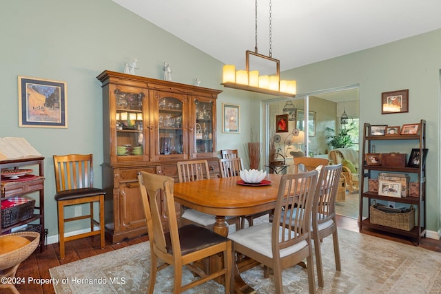 dining room with hardwood / wood-style flooring, vaulted ceiling, and an inviting chandelier