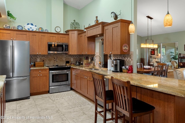 kitchen with tasteful backsplash, stainless steel appliances, decorative light fixtures, sink, and a breakfast bar