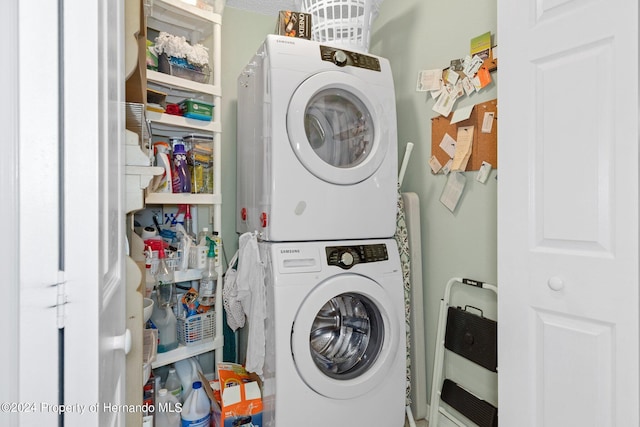 clothes washing area with stacked washing maching and dryer