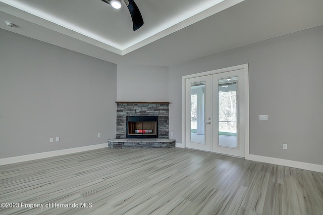 unfurnished living room featuring a stone fireplace, french doors, and light hardwood / wood-style flooring