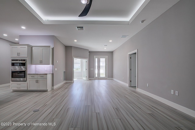 unfurnished living room featuring light wood-type flooring and french doors