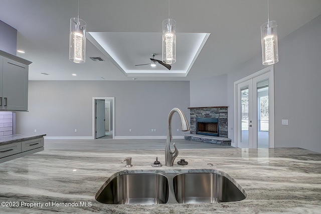 kitchen featuring gray cabinetry, decorative light fixtures, sink, and a fireplace