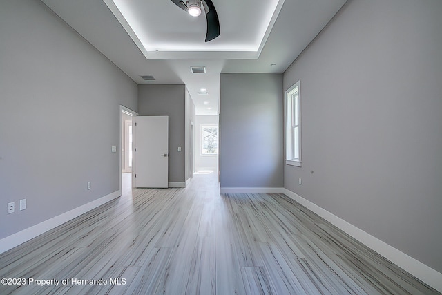 spare room featuring a raised ceiling and light hardwood / wood-style flooring