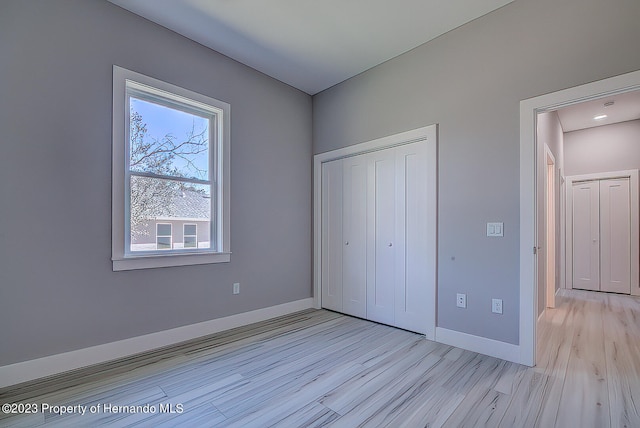 unfurnished bedroom with light hardwood / wood-style floors and a closet