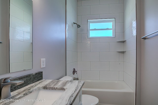 full bathroom featuring vanity, tiled shower / bath combo, and toilet