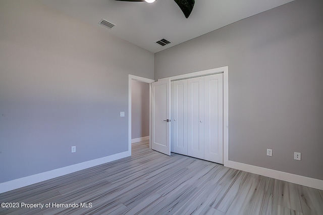 unfurnished bedroom featuring light wood-type flooring, ceiling fan, and a closet