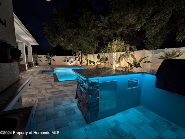 pool at twilight featuring a bar and a patio