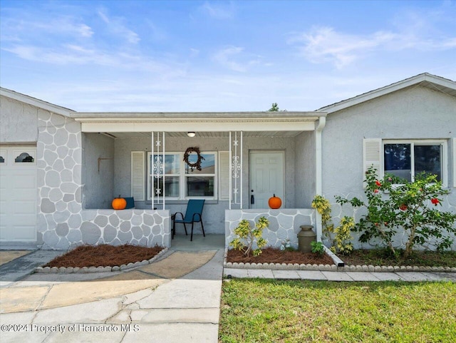 view of exterior entry with a garage and covered porch