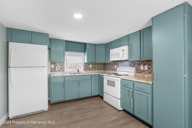 kitchen featuring a textured ceiling, sink, backsplash, light wood-type flooring, and white appliances