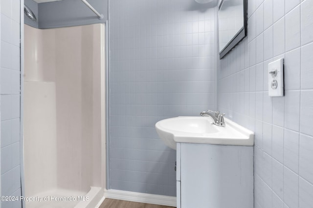 bathroom with tile walls, a shower, vanity, and hardwood / wood-style flooring