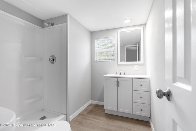 bathroom featuring walk in shower, wood-type flooring, vanity, and toilet