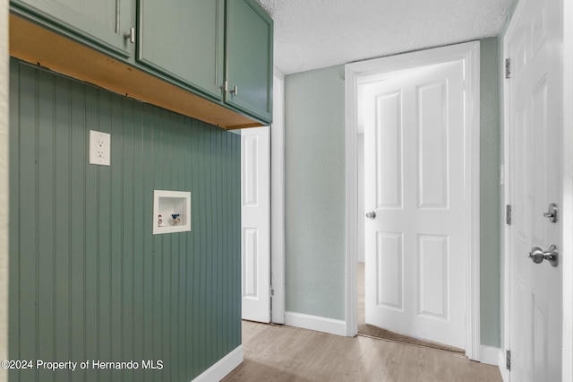 washroom with washer hookup, cabinets, a textured ceiling, and light hardwood / wood-style floors