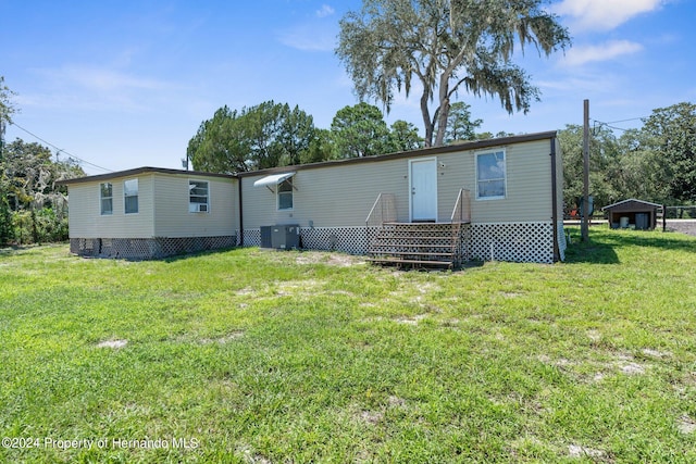 back of property featuring central AC and a lawn