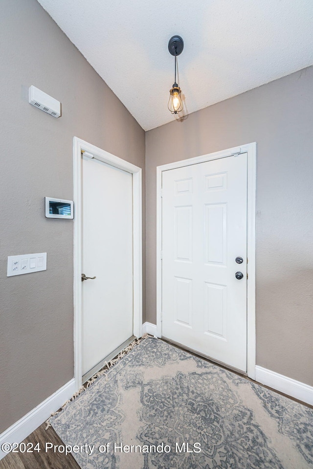 doorway to outside with hardwood / wood-style floors and vaulted ceiling