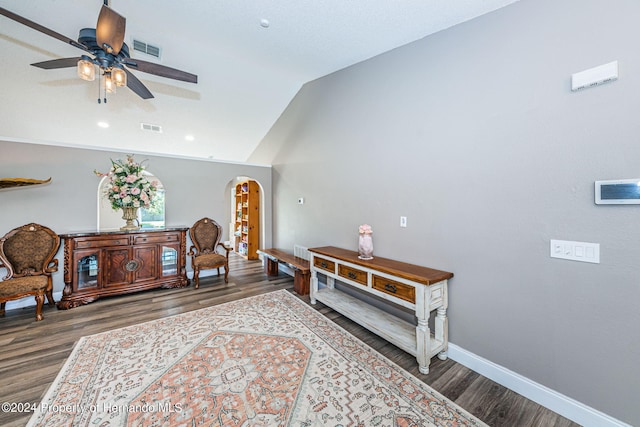 living area featuring dark wood-type flooring, ceiling fan, and vaulted ceiling