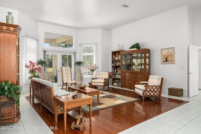 living area featuring a towering ceiling, light wood-type flooring, and french doors