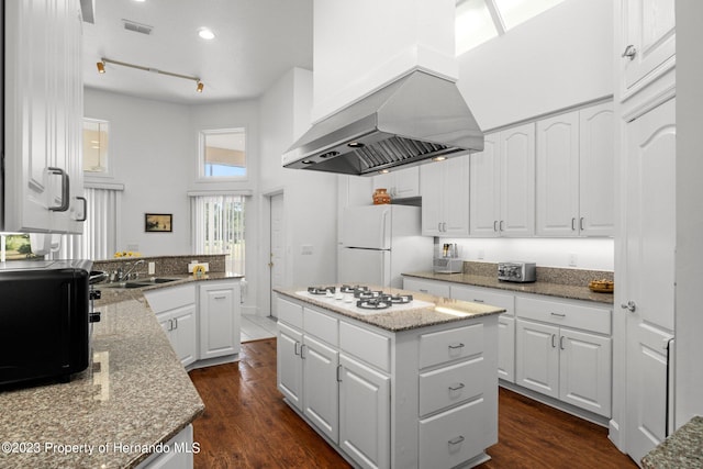 kitchen with ventilation hood, a kitchen island, white cabinets, dark wood-type flooring, and white appliances