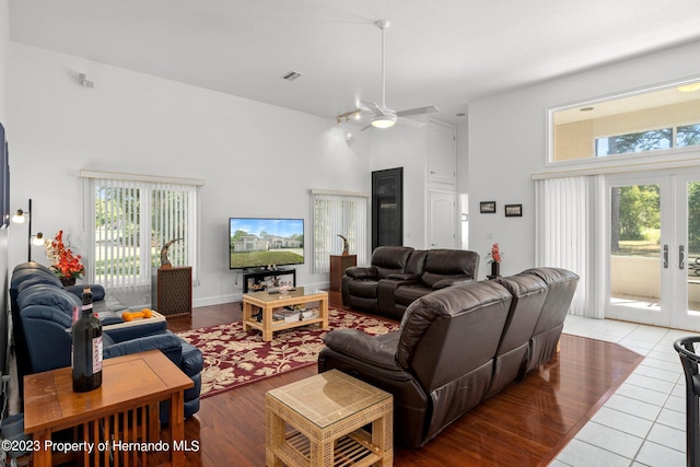 living room with a towering ceiling, french doors, hardwood / wood-style flooring, and ceiling fan