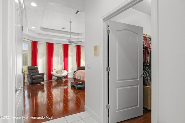 corridor featuring hardwood / wood-style floors, a textured ceiling, and a raised ceiling