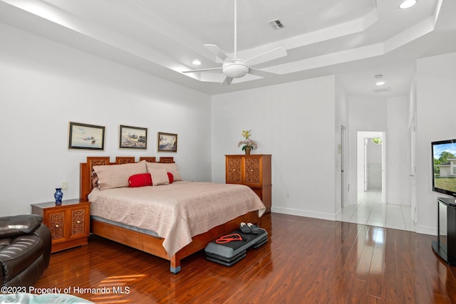 bedroom featuring dark wood-type flooring, ceiling fan, and a raised ceiling