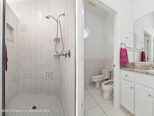 bathroom featuring tile walls, a bidet, vanity, tile patterned flooring, and toilet