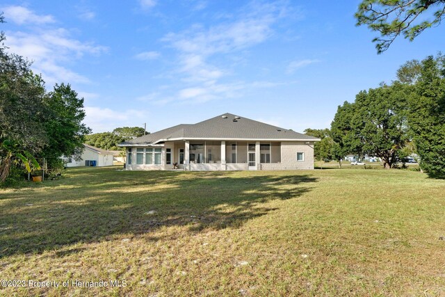 rear view of property with a lawn and a sunroom