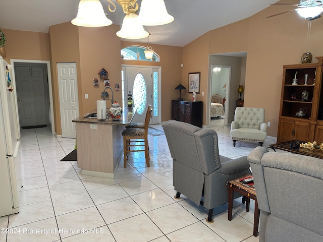 living room featuring ceiling fan with notable chandelier, light tile patterned flooring, and vaulted ceiling